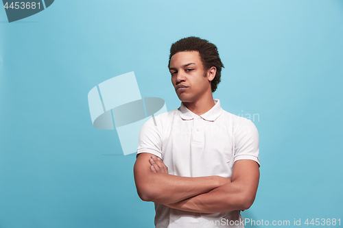 Image of Suspiciont. Doubtful pensive man with thoughtful expression making choice against blue background