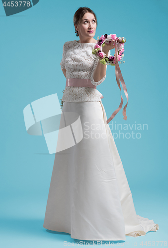 Image of beautiful woman wearing wedding dress against cyan background