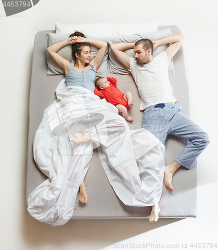 Image of Top view of happy family with one newborn child in bedroom.