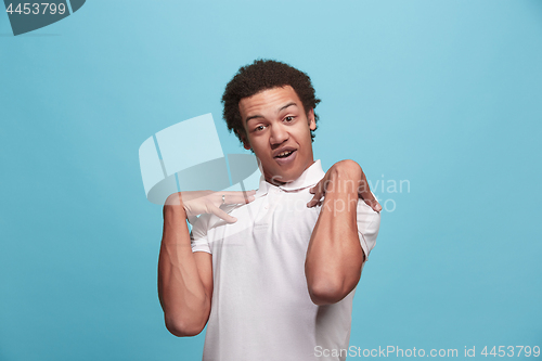 Image of Beautiful male half-length portrait isolated on blue studio backgroud. The young emotional surprised man