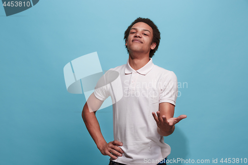 Image of Beautiful male half-length portrait isolated on blue studio backgroud. The young emotional surprised man