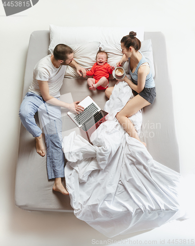 Image of Top view of happy family with one newborn child in bedroom.