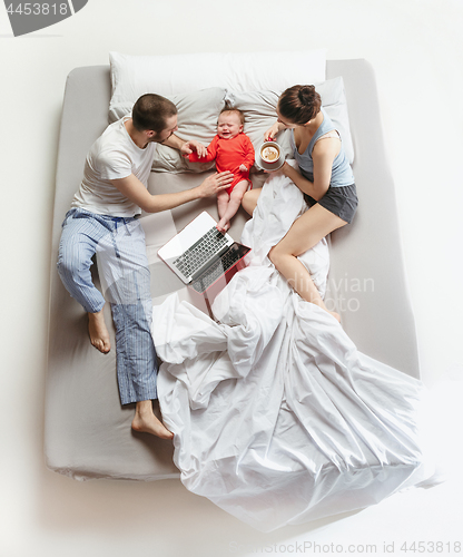 Image of Top view of happy family with one newborn child in bedroom.