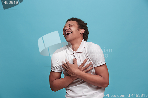 Image of The happy business man standing and smiling against blue background.