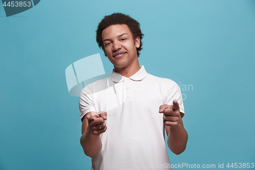 Image of The happy business man point you and want you, half length closeup portrait on blue background.