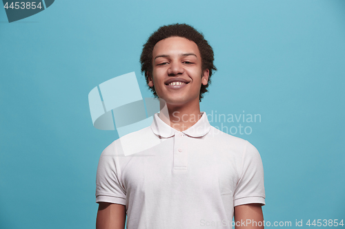 Image of The happy business man standing and smiling against blue background.