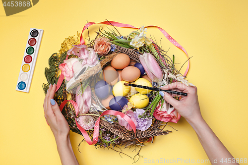 Image of Easter card. Painted Easter eggs in nest on yellow background