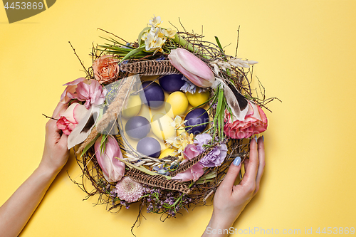 Image of Easter card. Painted Easter eggs in nest on yellow background