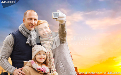 Image of family taking selfie by camera over sunset in city