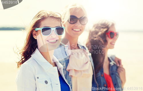 Image of group of smiling women in sunglasses on beach