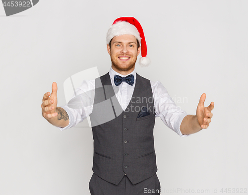Image of happy man in santa hat holding something imaginary