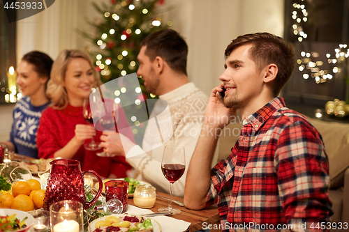 Image of man calling on smartphone at christmas dinner
