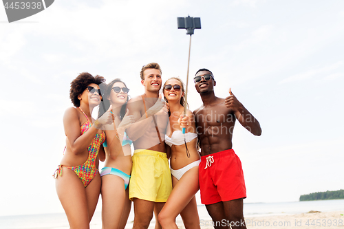 Image of friends taking selfie on beach and show thumbs up