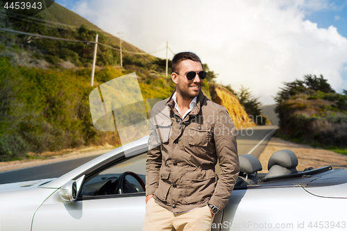 Image of man at convertible car over big sur hills