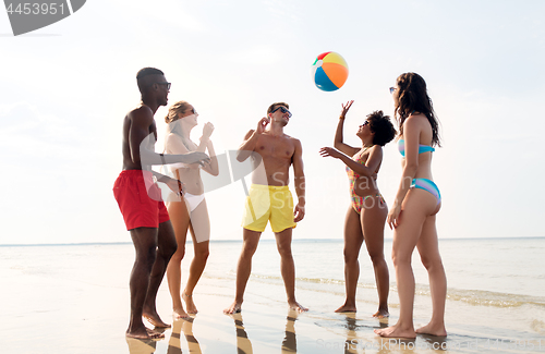 Image of friends playing with beach ball in summer