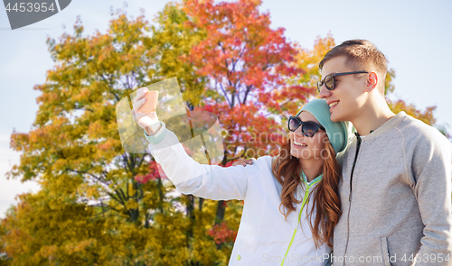 Image of couple taking selfie by smartphone in autumn park