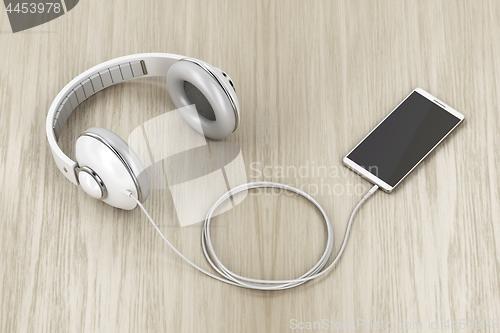 Image of Big white headphones and smartphone on wood table
