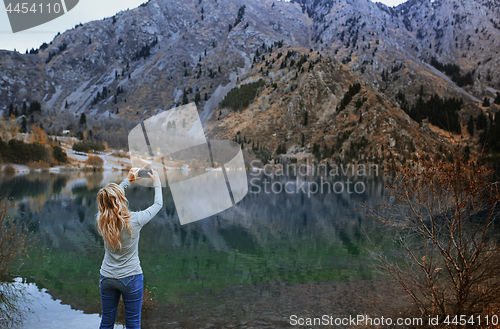 Image of Woman making mobile photo at the mountain lake