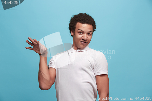 Image of Beautiful male half-length portrait isolated on blue studio backgroud. The young emotional surprised man