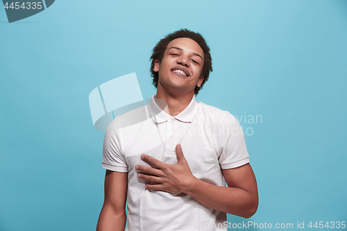 Image of The happy business man standing and smiling against blue background.