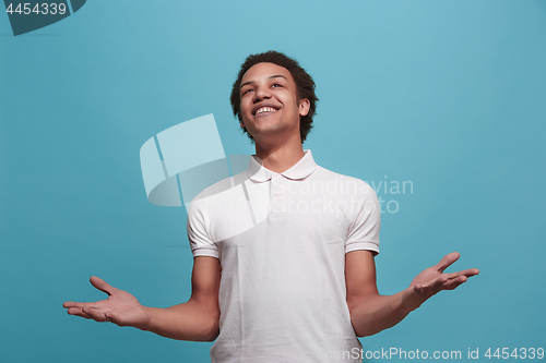 Image of The happy business man standing and smiling against blue background.