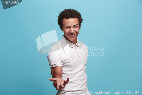 Image of Beautiful male half-length portrait isolated on blue studio backgroud. The young emotional surprised man