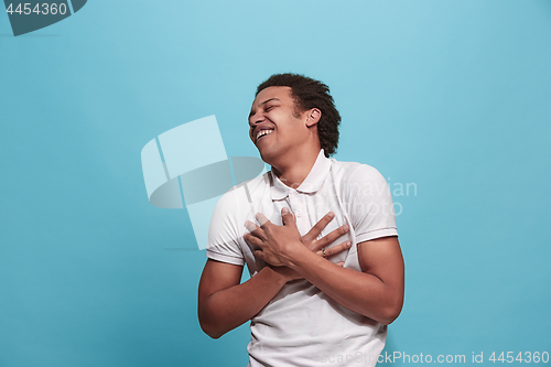 Image of The happy business man standing and smiling against blue background.