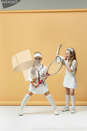 Image of Portrait of two girls as tennis players holding tennis racket. Studio shot.