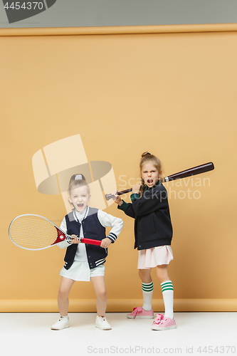 Image of Portrait of two girls as tennis players holding tennis racket. Studio shot.