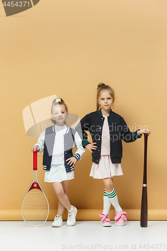 Image of Portrait of two girls as tennis players holding tennis racket. Studio shot.