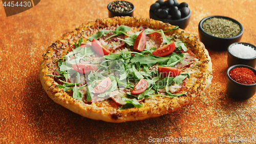 Image of Tasty pizza on a rusty background with spices, herbs and vegetables