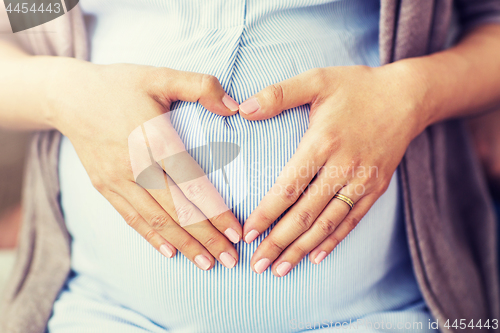 Image of close up of pregnant woman making heart on belly