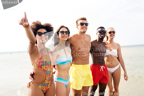 Image of happy friends hugging on summer beach