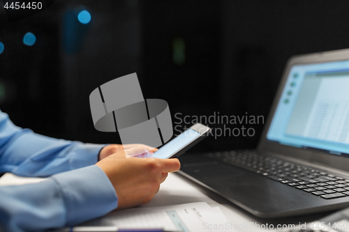 Image of close up of hands with smartphone at night office