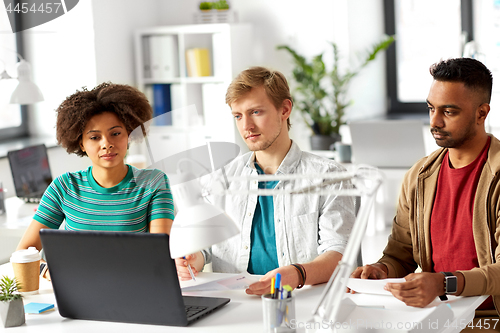 Image of happy creative workers with laptops at office