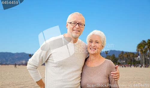 Image of happy senior couple hugging over venice beach