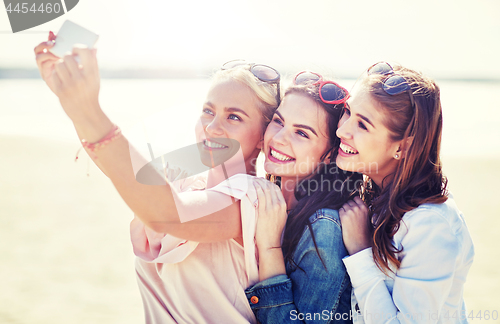 Image of group of smiling women taking selfie on beach