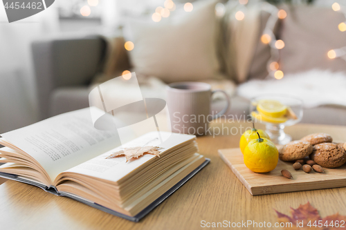 Image of book, lemon, tea and cookies on table at home