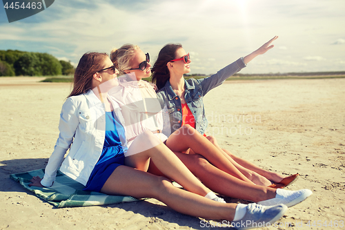 Image of group of smiling women in sunglasses on beach