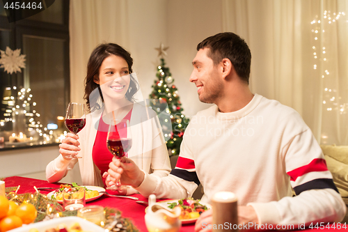 Image of happy couple drinking red wine at christmas dinner