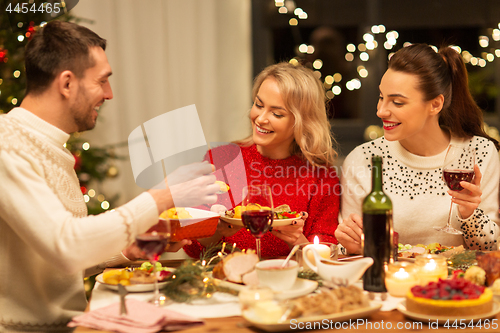 Image of happy friends having christmas dinner at home