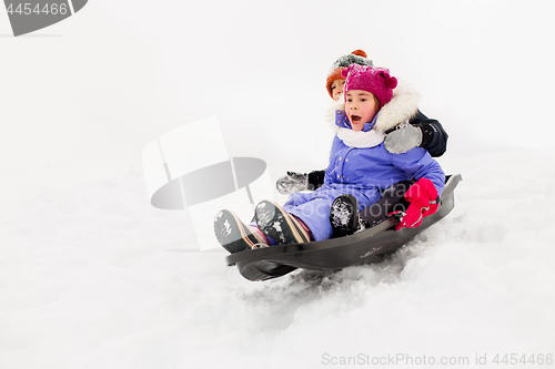 Image of kids sliding on sled down snow hill in winter