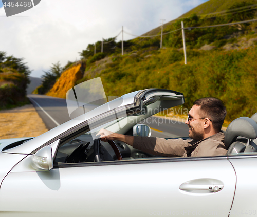 Image of man driving convertible car over big sur hills