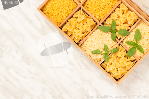 Image of Box with different types of pasta on marble background