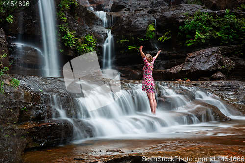Image of Adventurous female standing in waterfalls