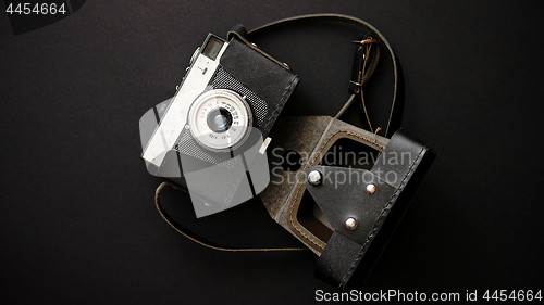 Image of Old retro film camera in leather case on black background