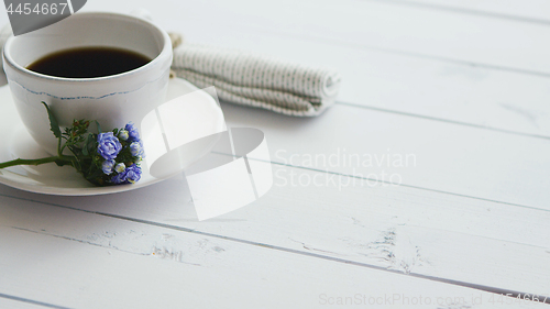 Image of Black coffee in white cup on bright wooden background.