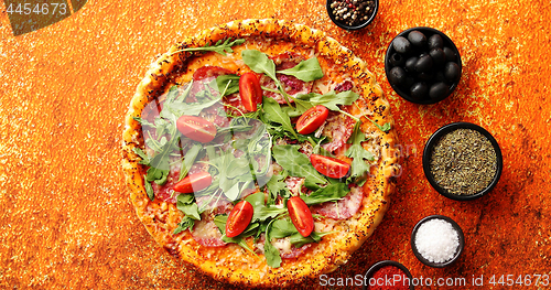 Image of Tasty pizza on a rusty background with spices, herbs and vegetables