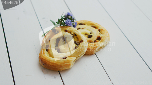 Image of Delicious pastry with raisins on white wooden table