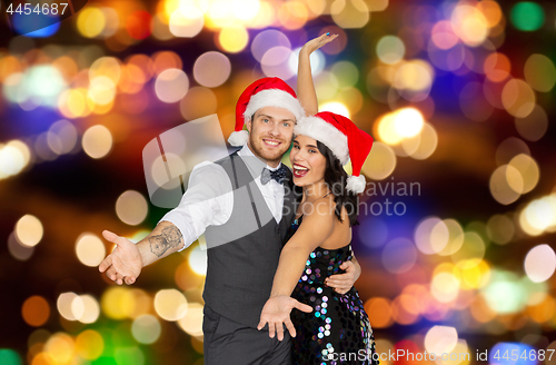 Image of happy couple in santa hats at christmas party